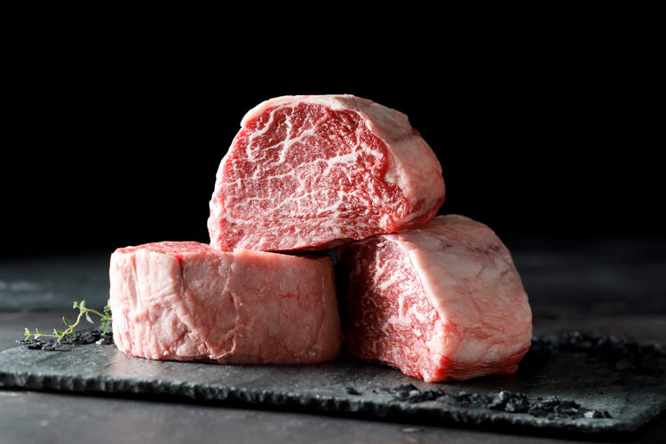 Three pieces of raw Irodori Wagyu beef on a dark surface with a black background
