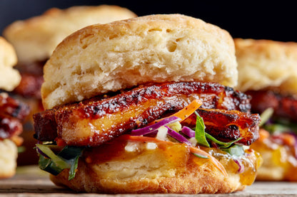 Pork Belly Slider on a biscuit with caramelized sliced pork and an Asian coleslaw
