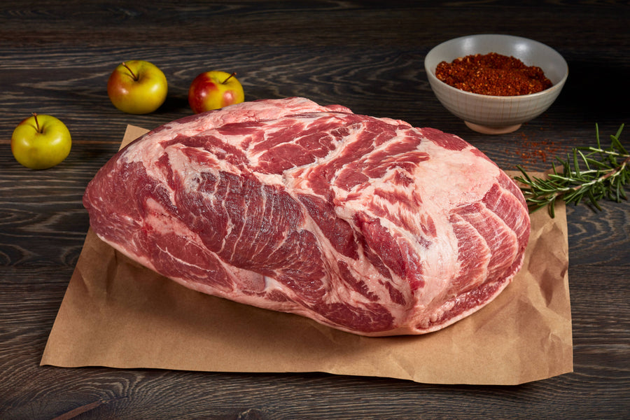 Raw Pork on brown paper with apples and a bowl of spices on a wooden surface